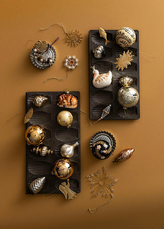 Decorative brass ornaments on black trays against a brown background