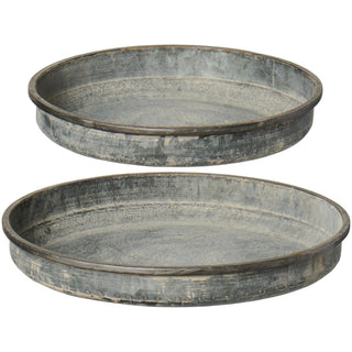 Two round weathered grey metal candle trays of different sizes with a low raised edge, stacked on a white background