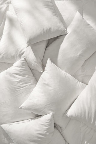 Overhead view of plump white cushion fillers arranged closely together in sunlight