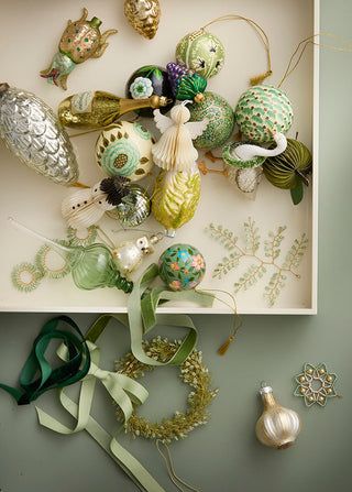 Collection of decorative ornaments on a white shelf with a green background