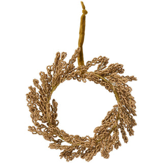 Round wreath ornament made of gold-tone beads with a mustard velvet ribbon hanger on a white background
