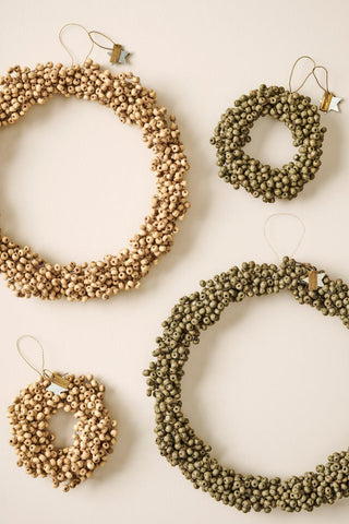 Four wooden bead wreaths in natural and olive green tones hanging on a wall