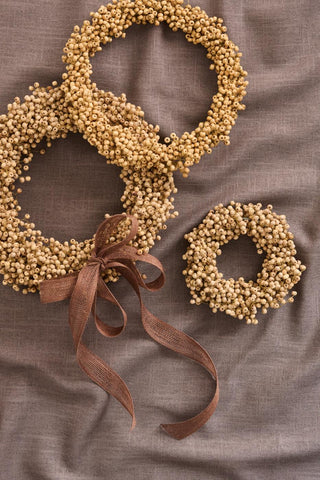 Overlapping natural wooden bead wreaths of different sizes tied with a brown ribbon, laid on brown linen fabric